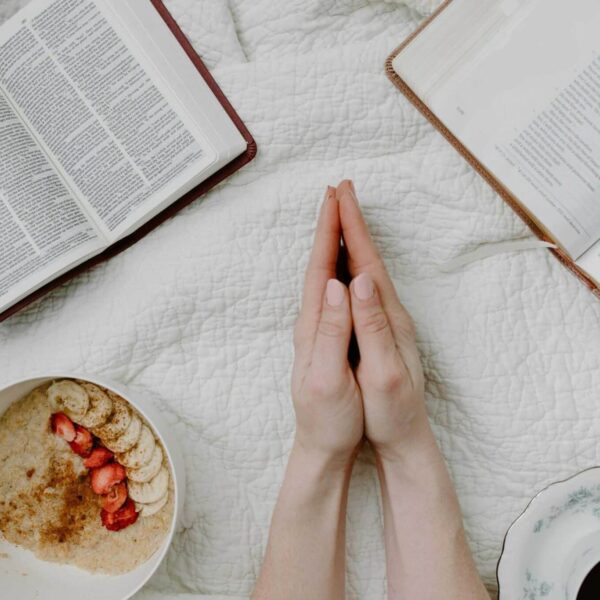 A serene morning scene with a person praying, an open Bible, oatmeal, and coffee. Daily devotion