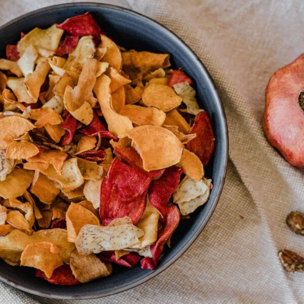 healthy chips, recipes, A stylish presentation of healthy dried fruit chips in a bowl with a pomegranate on textile background.