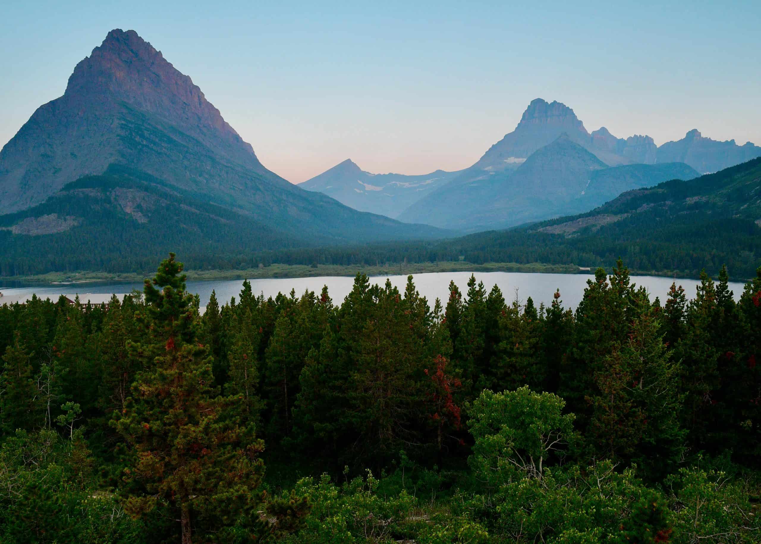 Serene mountain landscape featuring Grinnell Point and lush forest in Glacier National Park, Montana.