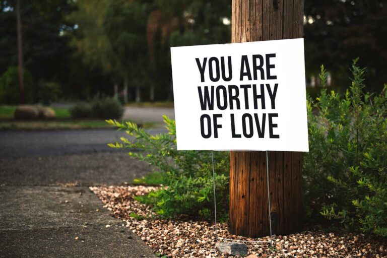 A positive message sign "You are worthy of love" in a park setting. self-compassion