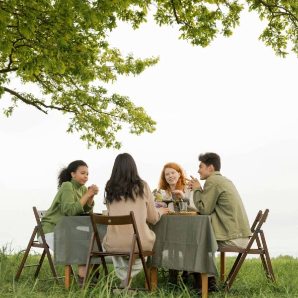 Gen Z, intentional, A diverse group of friends at an outdoor picnic, enjoying food and conversation under a tree.