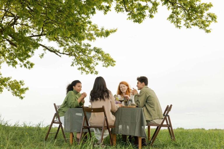 Gen Z, intentional, A diverse group of friends at an outdoor picnic, enjoying food and conversation under a tree.