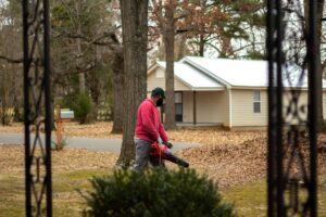 A man cleans fallen leaves with a blower in a residential neighborhood during autumn. leaf vacuums