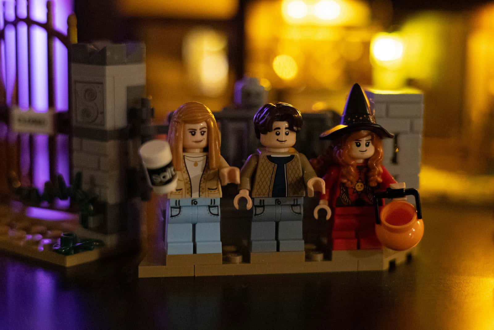 Three lego figures in a castle setting, Allison Watts, Max Dennison and Dani Dennison stand outside the gate in this LEGO set recreation from the 1993 classic "Hocus Pocus."