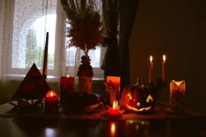 a table topped with candles and pumpkins next to a window, Halloween decoration