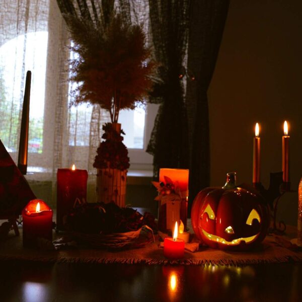 a table topped with candles and pumpkins next to a window, Halloween decoration