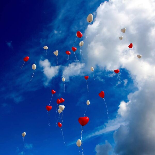 This is a photograph of heart-shaped balloons floating in the sky. It is important to consider feelings when considering ethical non-monogamy.
