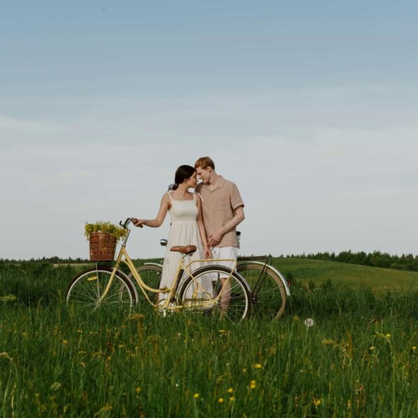 Loving couple with a bike in a grassy summer field, enjoying nature outdoors, healthy relationships