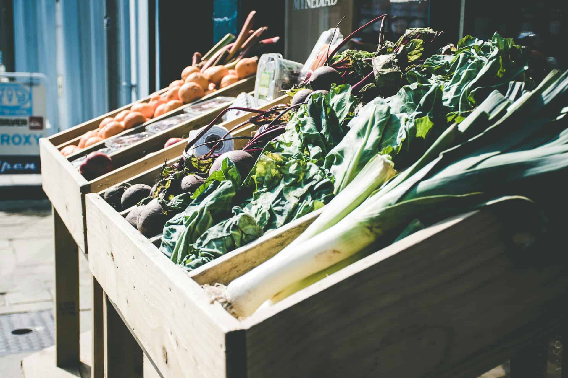 An array of fresh vegetables at an outdoor market stall, showcasing green leafy produce.