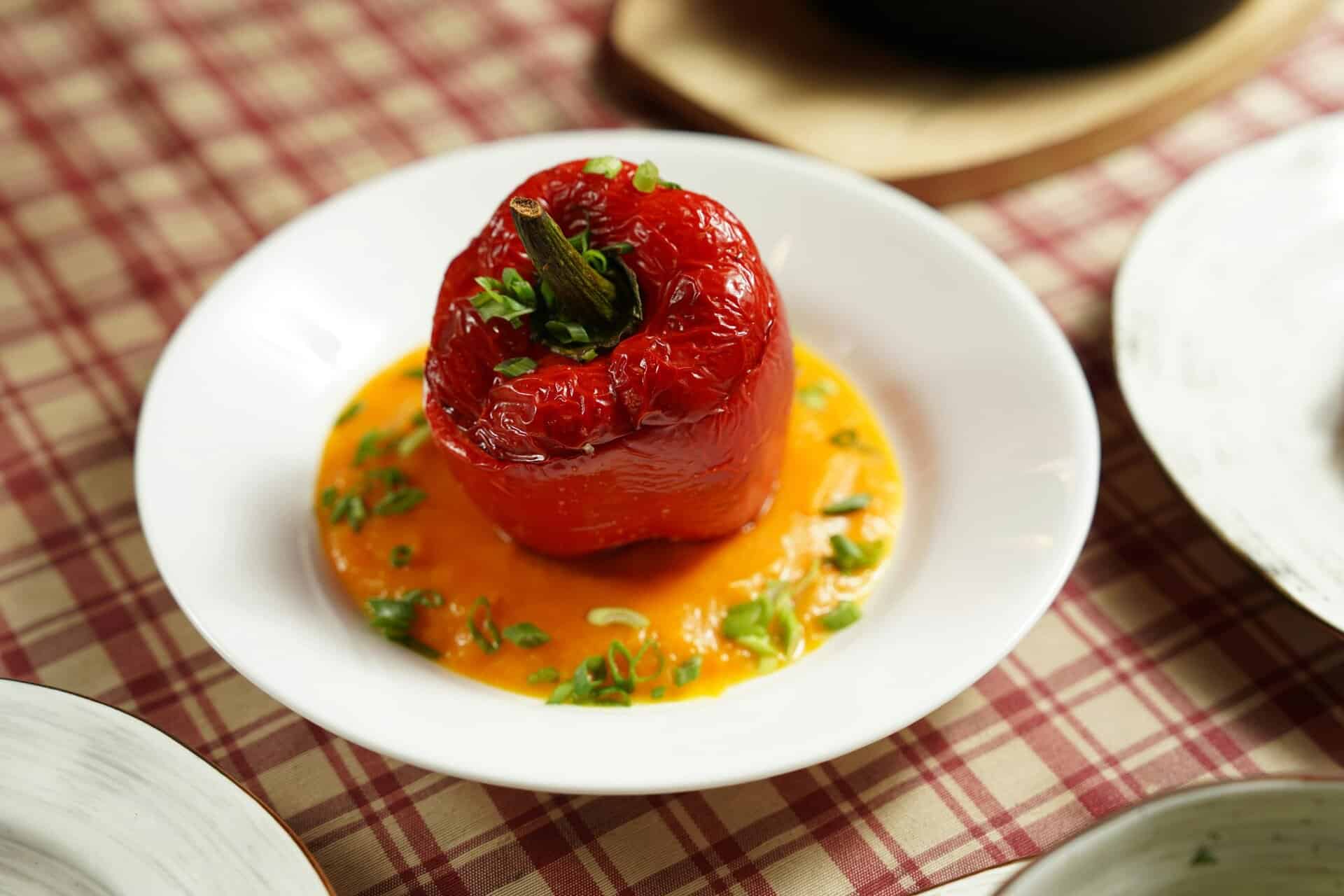 Savor a gourmet stuffed red bell pepper on creamy sauce, perfect for any meal.