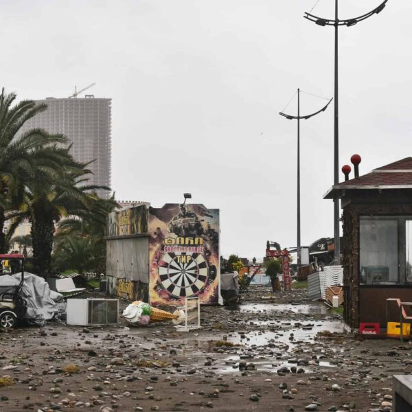 City street filled with storm debris and damaged structures under a cloudy sky., Jamaica