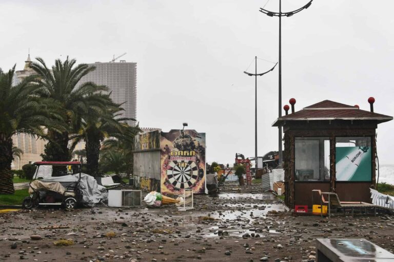 City street filled with storm debris and damaged structures under a cloudy sky., Jamaica