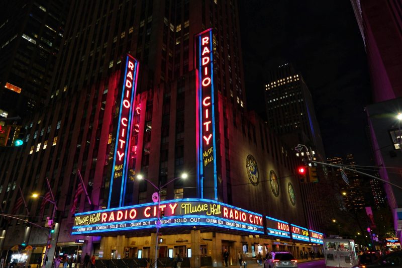 Vibrant neon lights of Radio City Music Hall illuminate New York City at night.