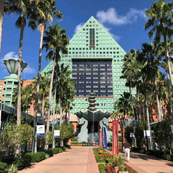 Iconic Swan Hotel at Walt Disney World in Kissimmee, FL with lush palm trees and clear skies.