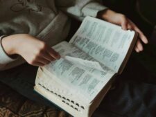 A person flipping through pages of a book, capturing a moment of thoughtful reading indoors, daily devotion