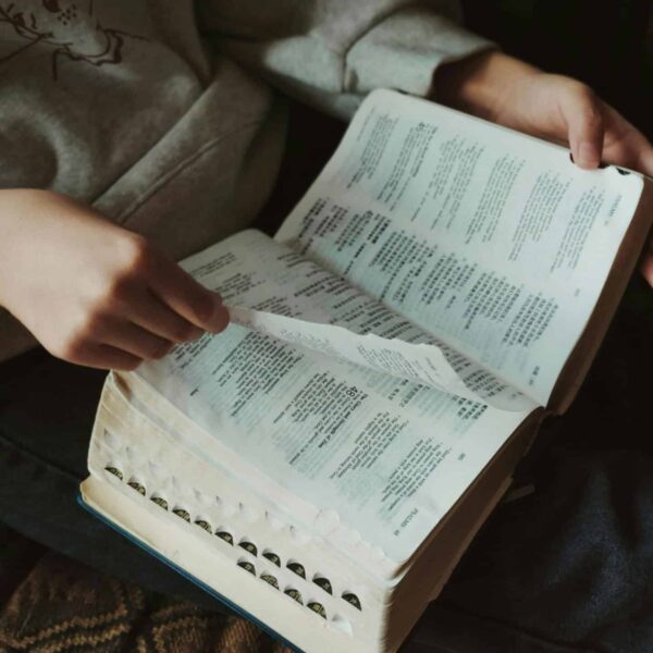 A person flipping through pages of a book, capturing a moment of thoughtful reading indoors, daily devotion