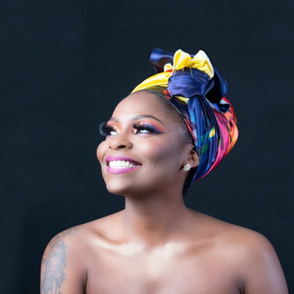 A beautiful portrait of a smiling woman wearing a vibrant headwrap, exuding joy and elegance. Glowing skin from good microbiome, good gut health.