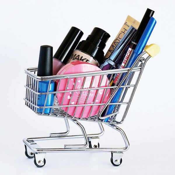 Miniature shopping cart filled with a variety of cosmetics on a white background. beauty releases