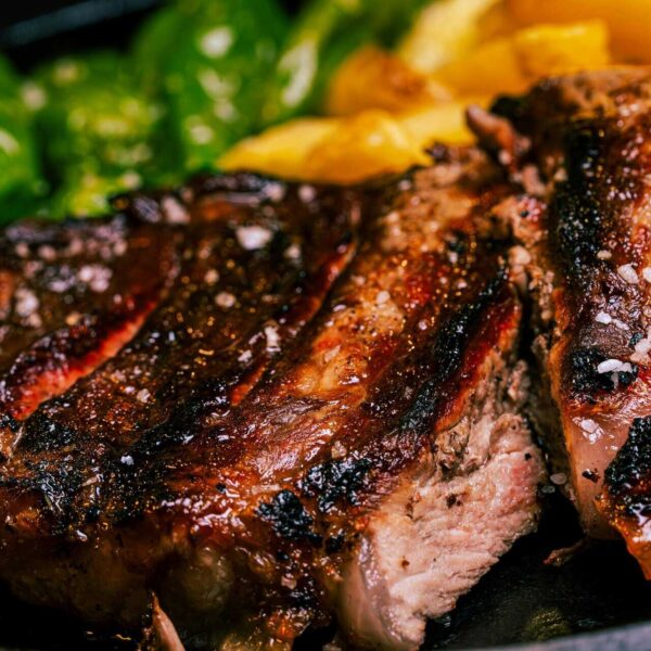Juicy grilled steak seasoned to perfection, accompanied by fresh vegetables, iron-rich food. Healthy eating.