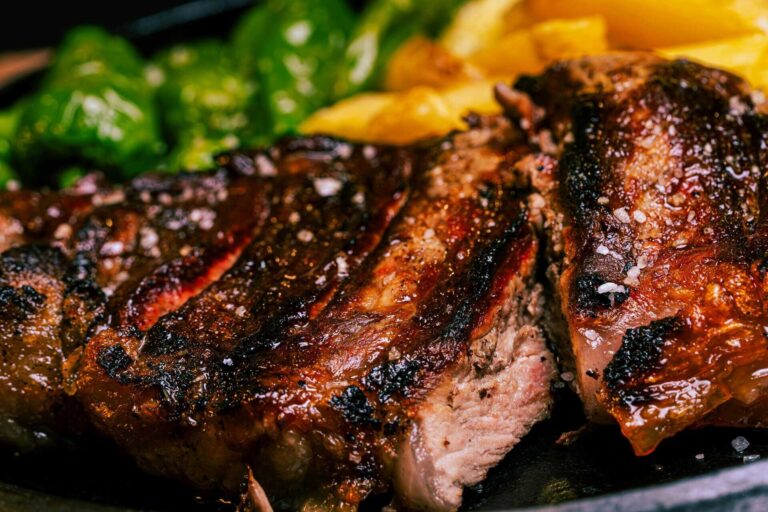 Juicy grilled steak seasoned to perfection, accompanied by fresh vegetables, iron-rich food. Healthy eating.