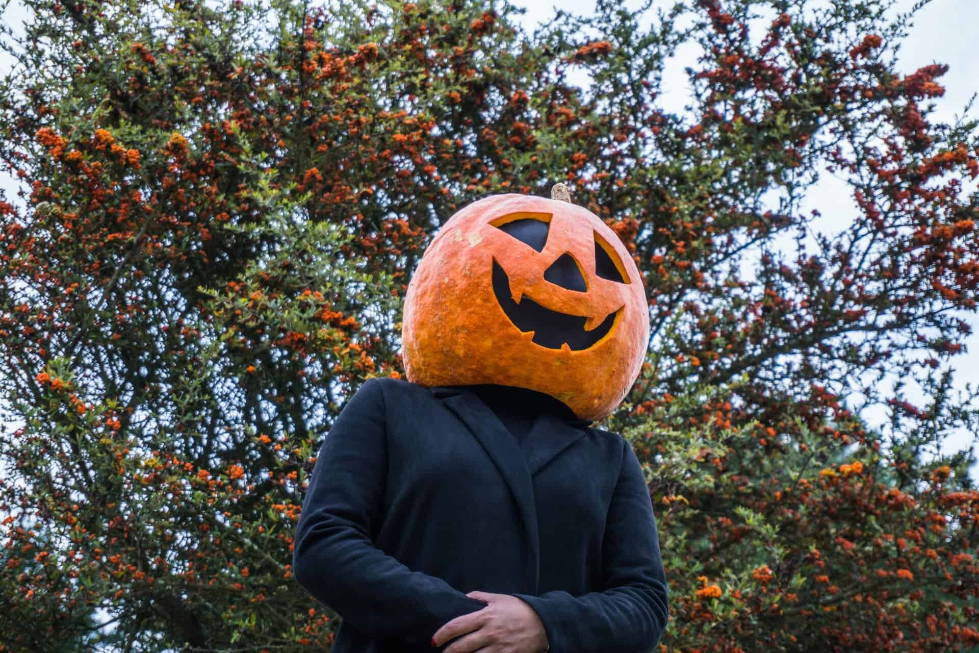 Person in pumpkin head costume outdoors surrounded by autumn foliage in Guasca, Colombia.