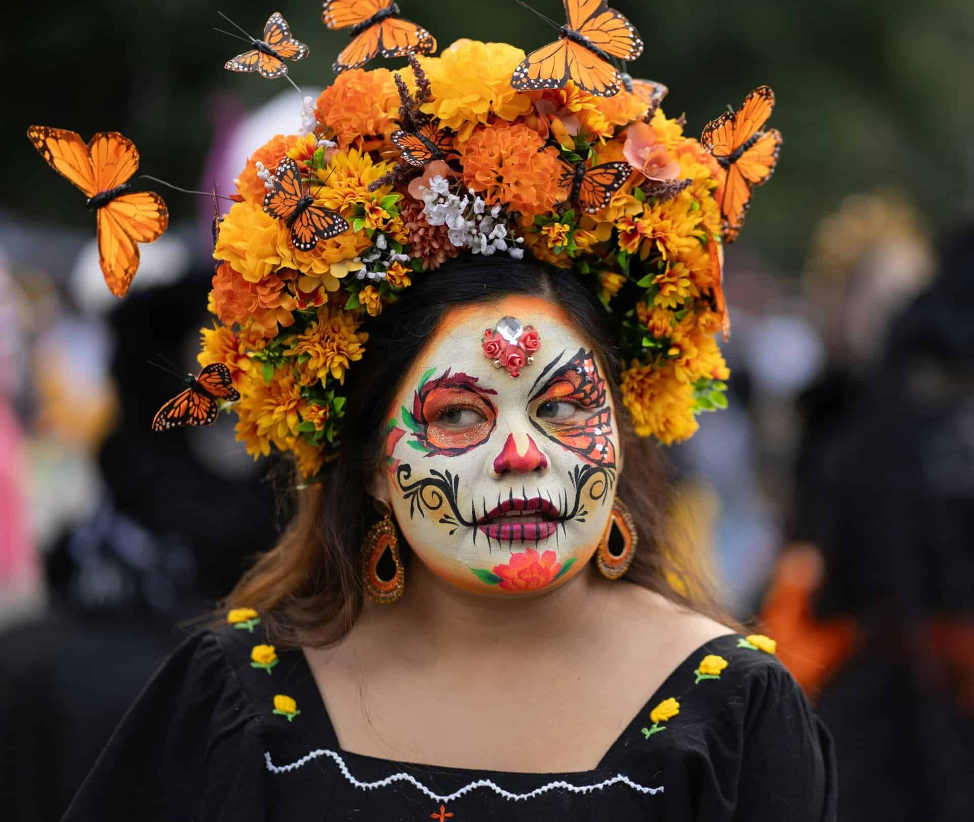 Vibrant and colorful Catrina makeup with butterfly and floral headdress in Mexico City's Day of the Dead celebration.