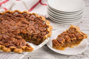 Mouthwatering pecan pie with a slice served on a white plate. Perfect for desserts or southern cuisine enthusiasts. Fall food, pecans,