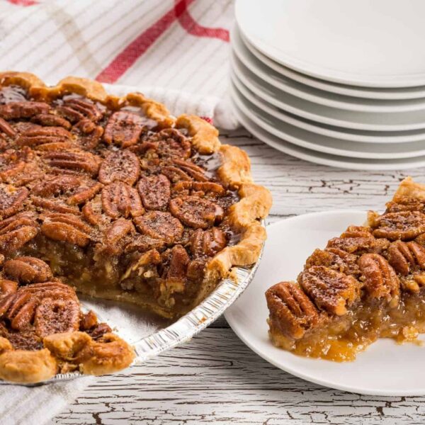Mouthwatering pecan pie with a slice served on a white plate. Perfect for desserts or southern cuisine enthusiasts. Fall food, pecans,