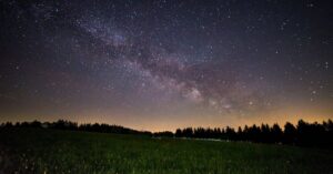 A breathtaking view of a starry night sky over a quiet field, showcasing the Milky Way. planetary returns