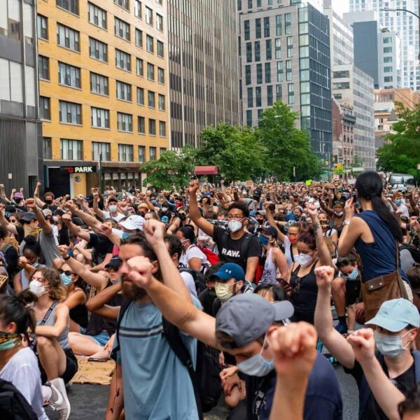 A large crowd of diverse protesters raising fists in a city street during daytime. Hollywood Stars Rally