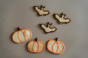 This is a photograph of cookies shaped like bats and pumpkins. Themed snacks can add to the fun of a movie night.