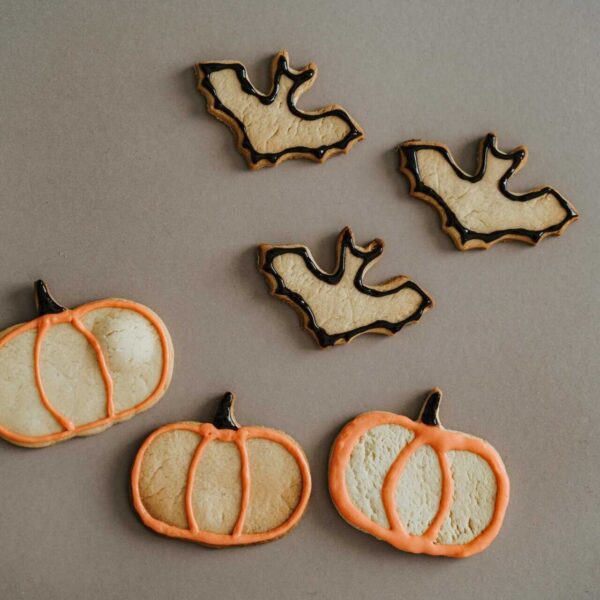This is a photograph of cookies shaped like bats and pumpkins. Themed snacks can add to the fun of a movie night.