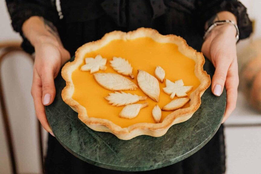This is a photograph of someone holding a pumpkin pie. Fall dessert recipes can help make autumn wonderful.