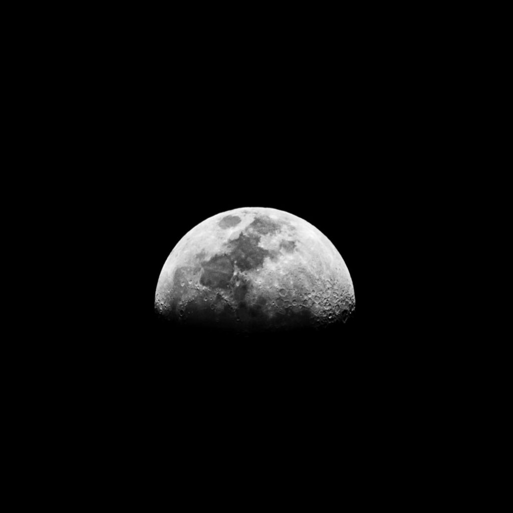 Stunning black and white photo of the half moon against a dark night sky. Ophiuchus daily forecast.