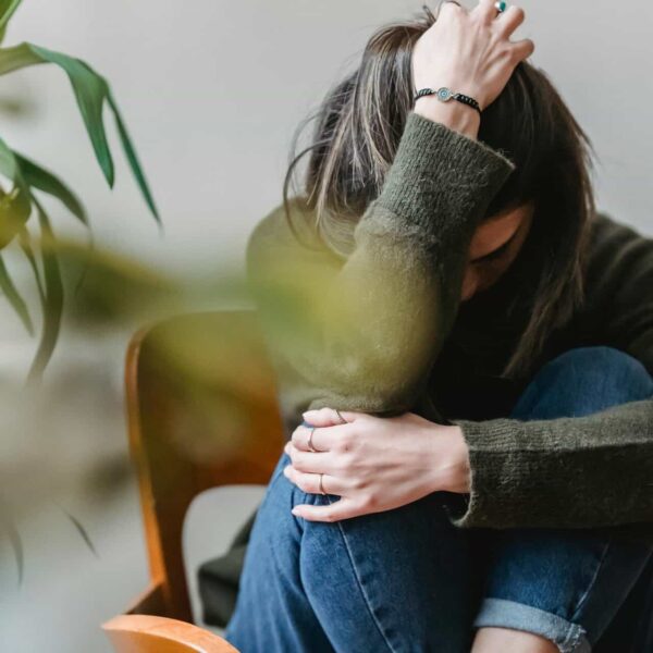 This is a photograph of a woman on a chair expressing sadness. Emotionally haunting someone may be a result of unresolved relationship difficulties.