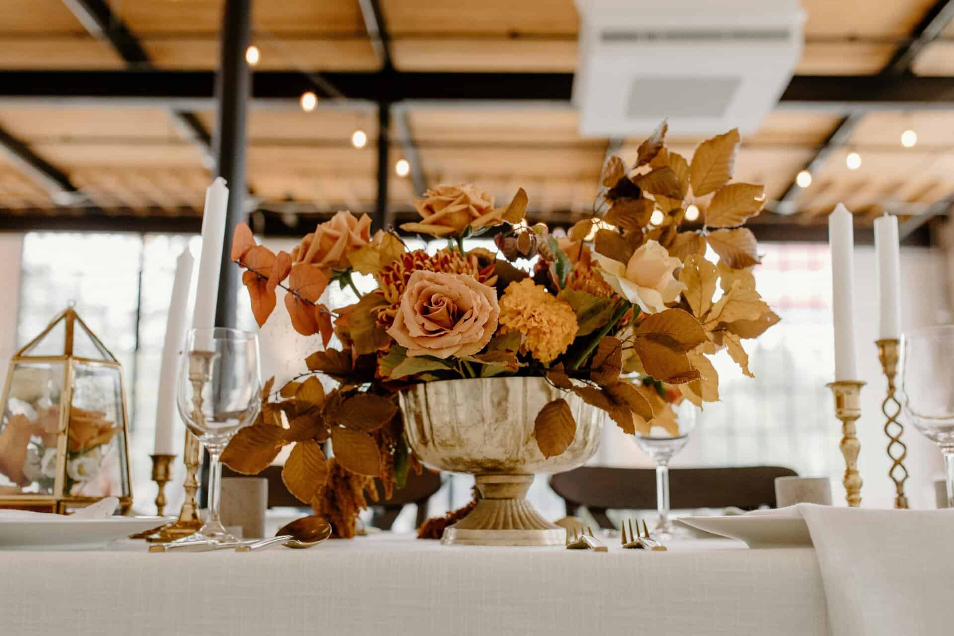 This photograph features a fall flower arrangement on an elegantly-set table. An autumn bouquet can add beauty to a room.