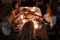 Four friends enjoying a candlelit dinner indoors with wine and conversation.