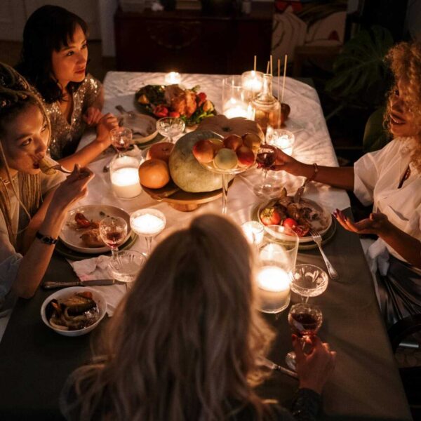 Four friends enjoying a candlelit dinner indoors with wine and conversation.