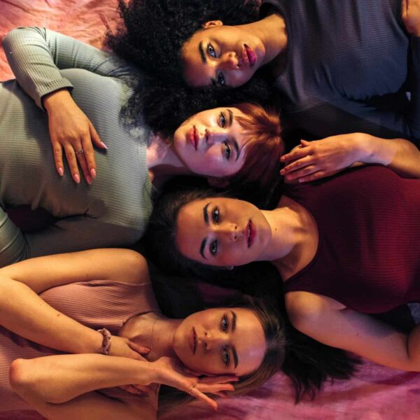 Empowered diverse women lying on pink fabric, showing unity and beauty. Women's Health and Depression.