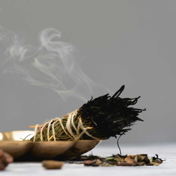 Calm and spiritual atmosphere with sage smudge burning in a ritual setting, aura cleansing.