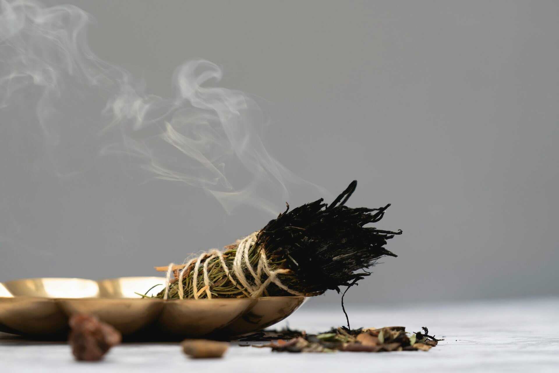 Calm and spiritual atmosphere with sage smudge burning in a ritual setting, aura cleansing.