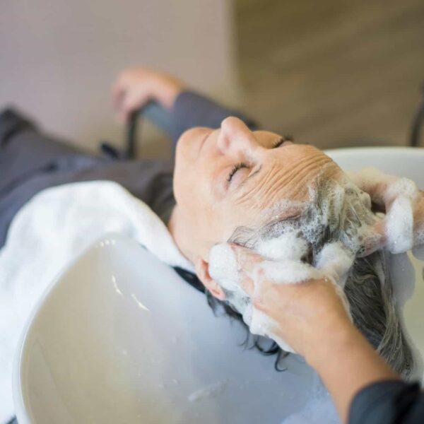 Woman enjoying a relaxing hair wash with shampoo and massage in a modern hair salon.