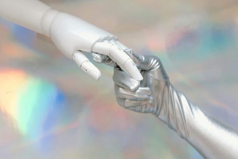Close-up of a robot hand and silver-gloved hand touching, symbolizing human-robot connection. OpenAI says AI relationships are not happening.