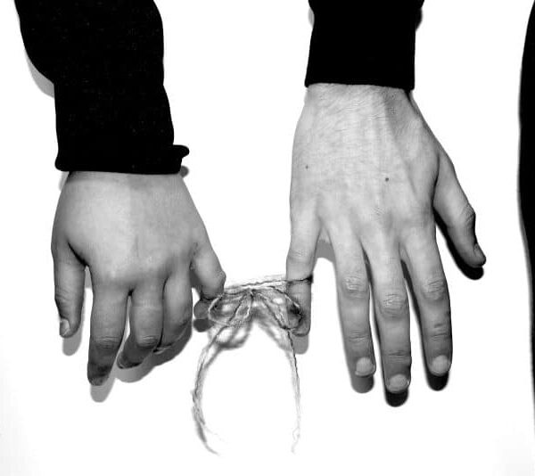 two hands holding a string tied to a tie