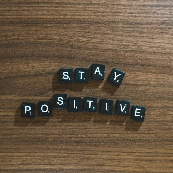 the word stay positive spelled in scrabble type on a wooden surface