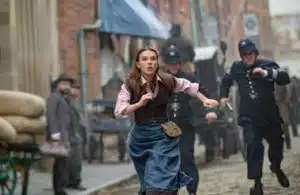 Millie Bobbie Brown as Enola Holmes running through the streets.