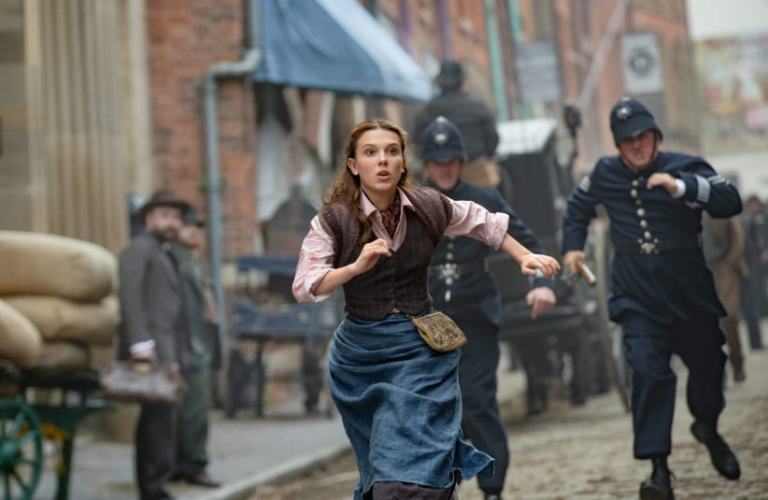 Millie Bobbie Brown as Enola Holmes running through the streets.