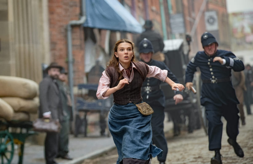 Millie Bobbie Brown as Enola Holmes running through the streets.