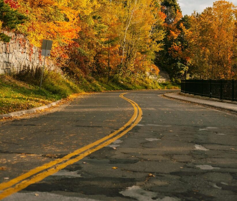 A serene road winding through vibrant autumn foliage, perfect for seasonal themed projects. thanksgiving stress free travel
