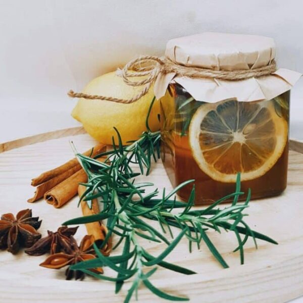 Artistic arrangement of lemon, herbs, and honey jar for DIY herbal tea.